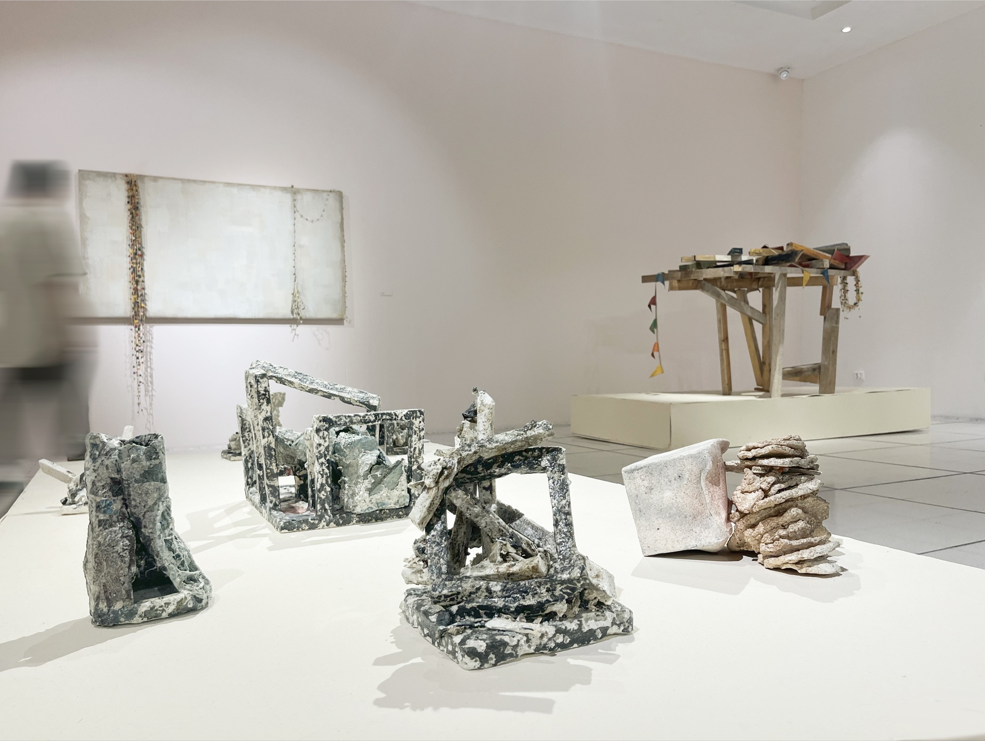 Five ceramic structures on the plinth; at the right, a wooden structure hung with bunting by another artist