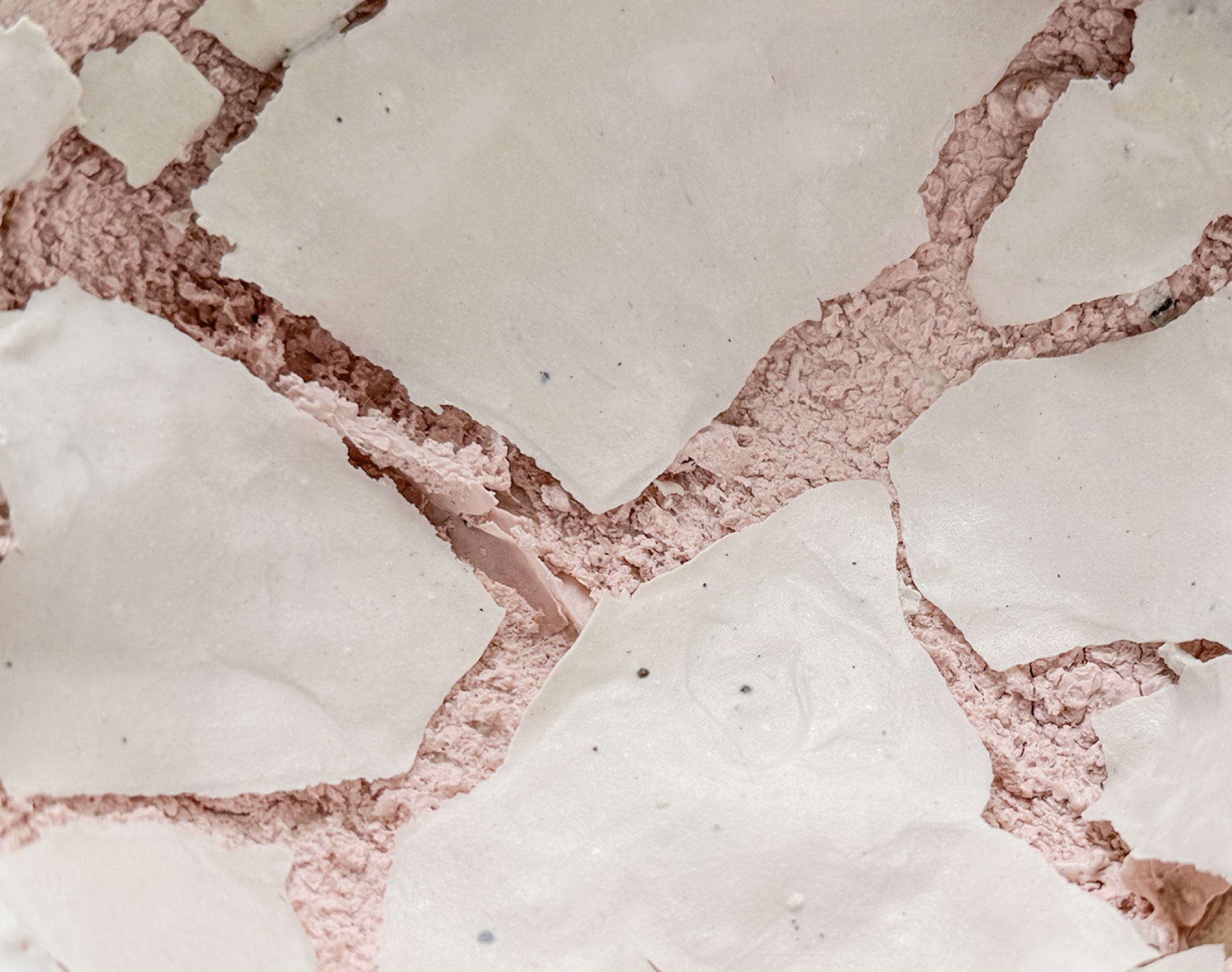 Detail: plates of white glaze lifted and split apart over the pink body beneath