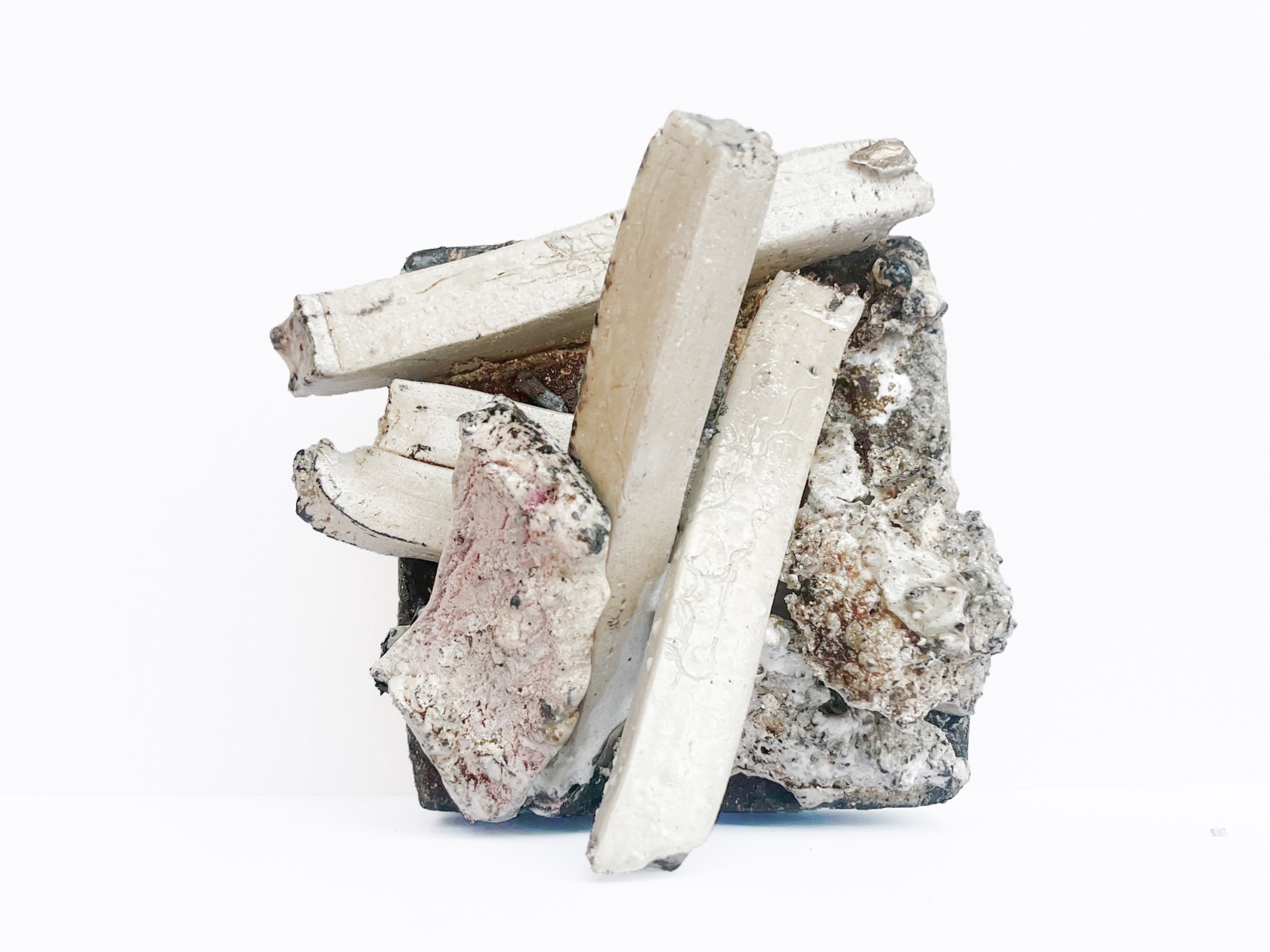 The smaller piece: pale ceramic bars stacked and crossed against a dark encrusted block