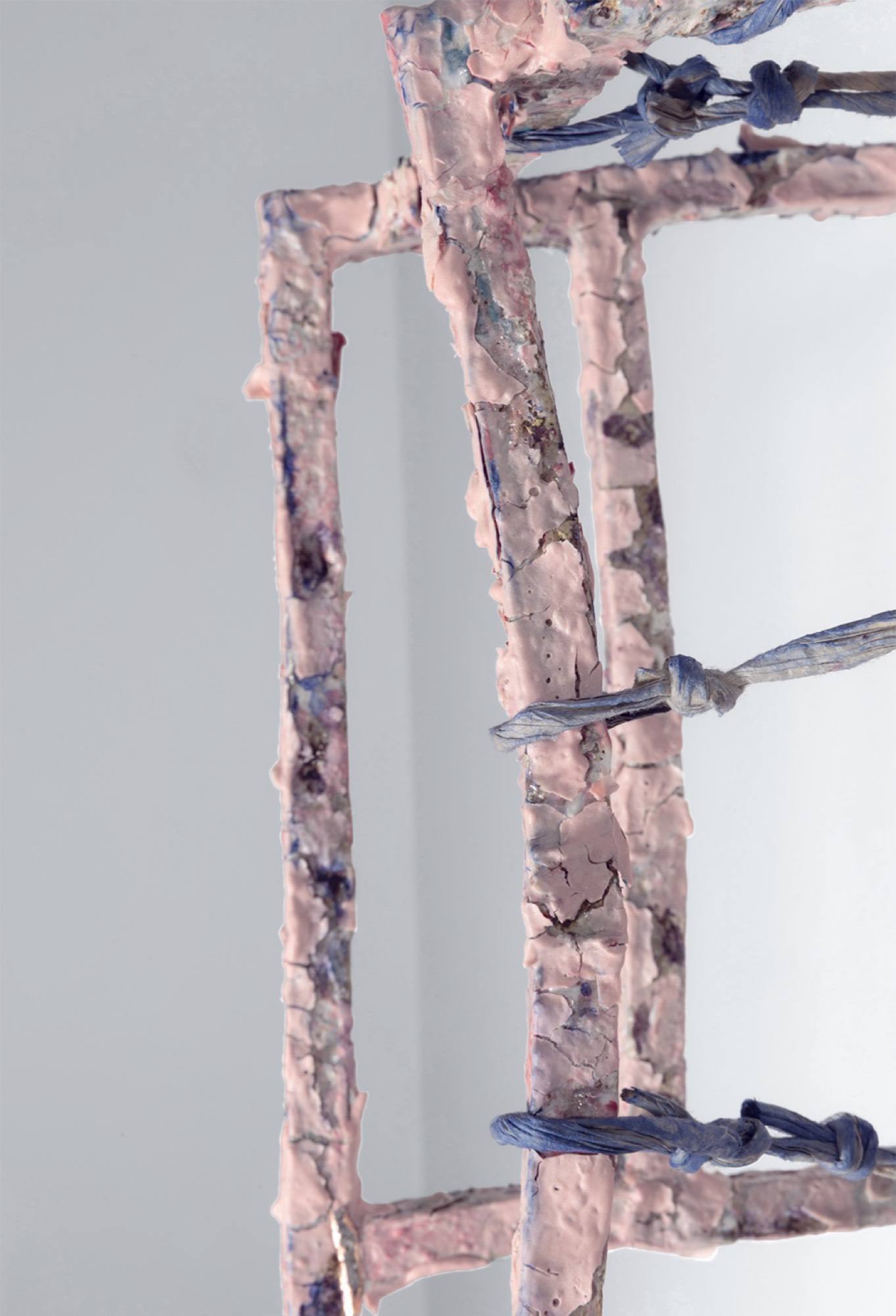 Detail of the grid: flaking porcelain skin and a knotted paper cord