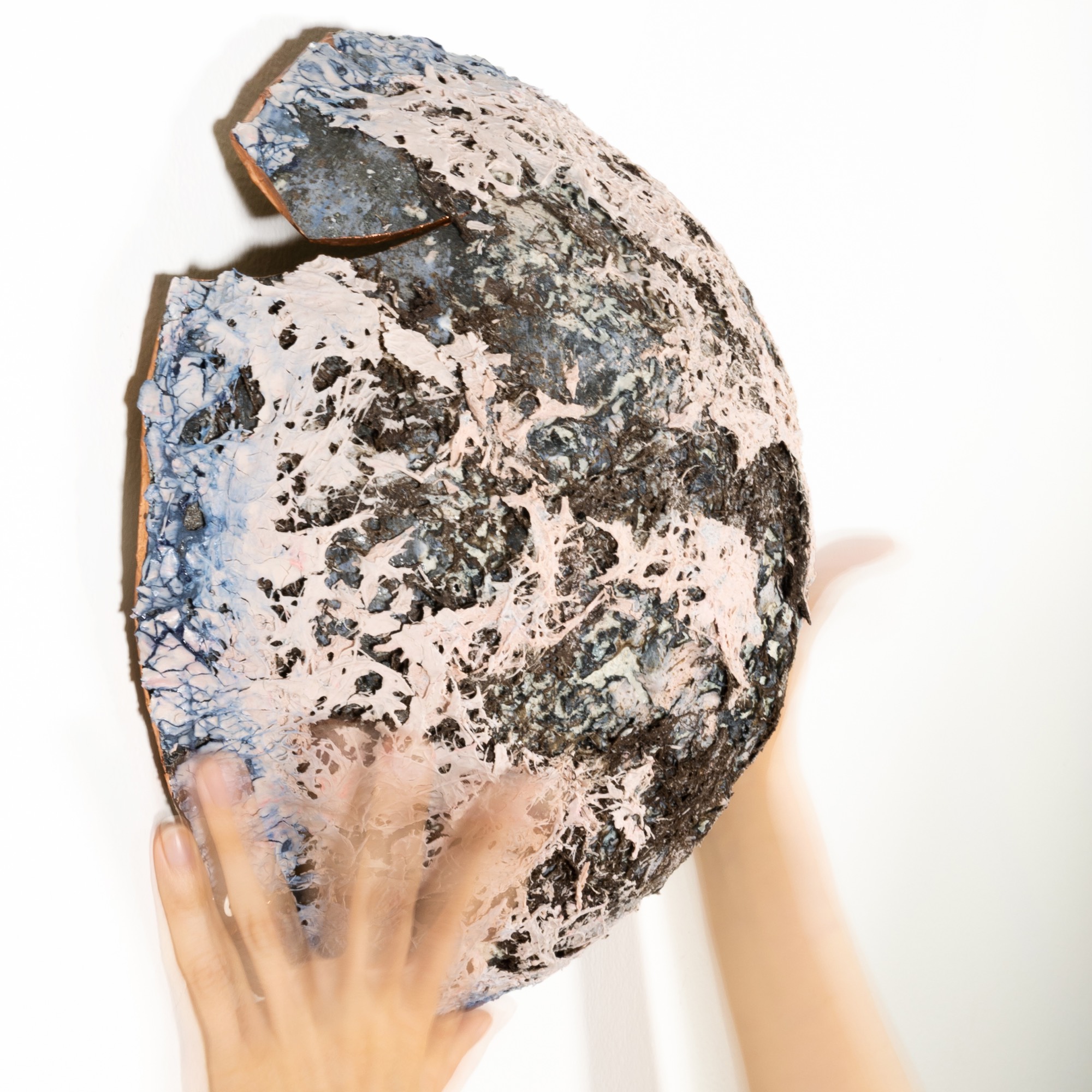 The disc held against the wall in two hands, showing its scale