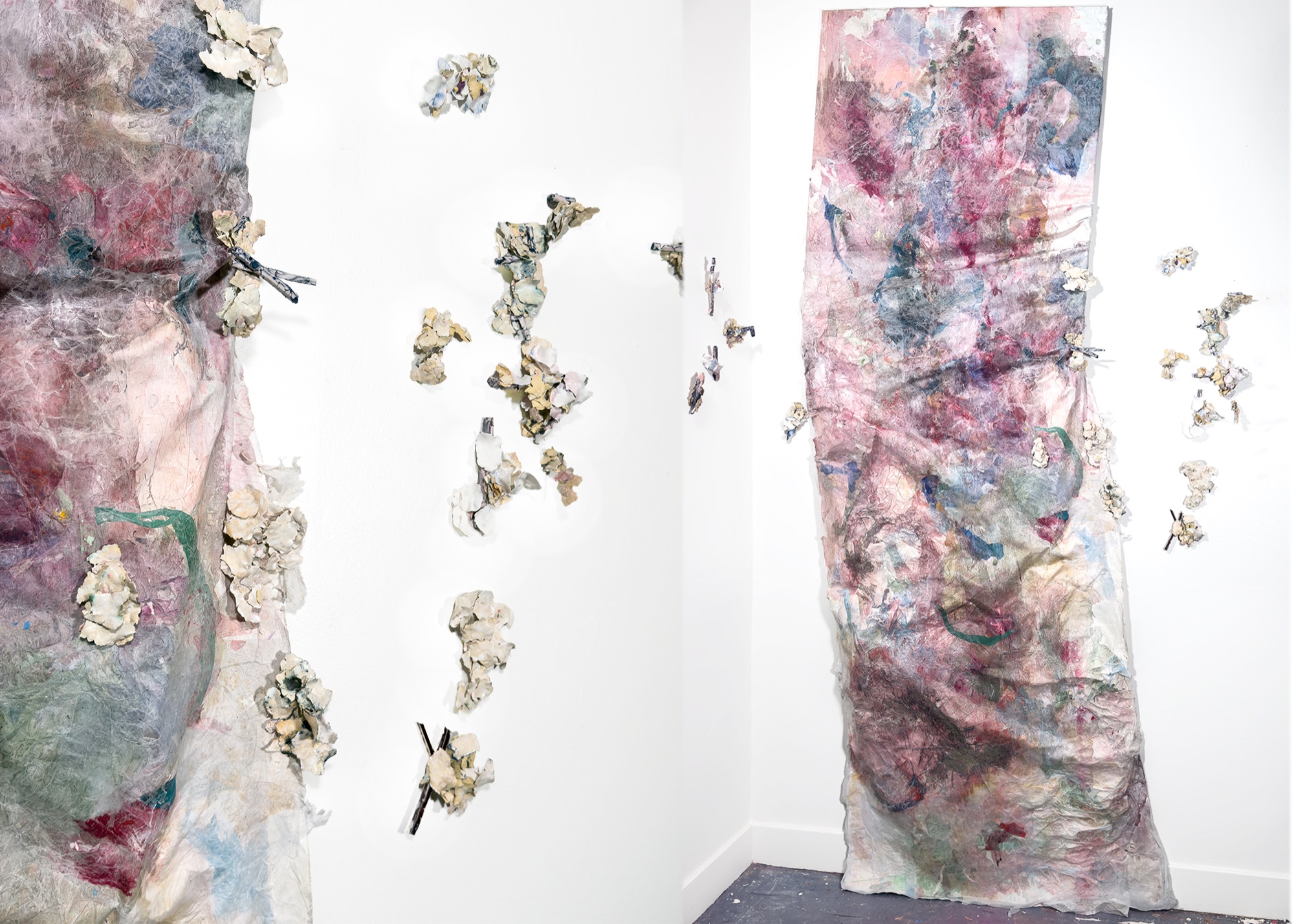 Somewhere Better – This Place — two tall paper panels hung on either side of a room corner, ceramic fragments scattered across the walls between them