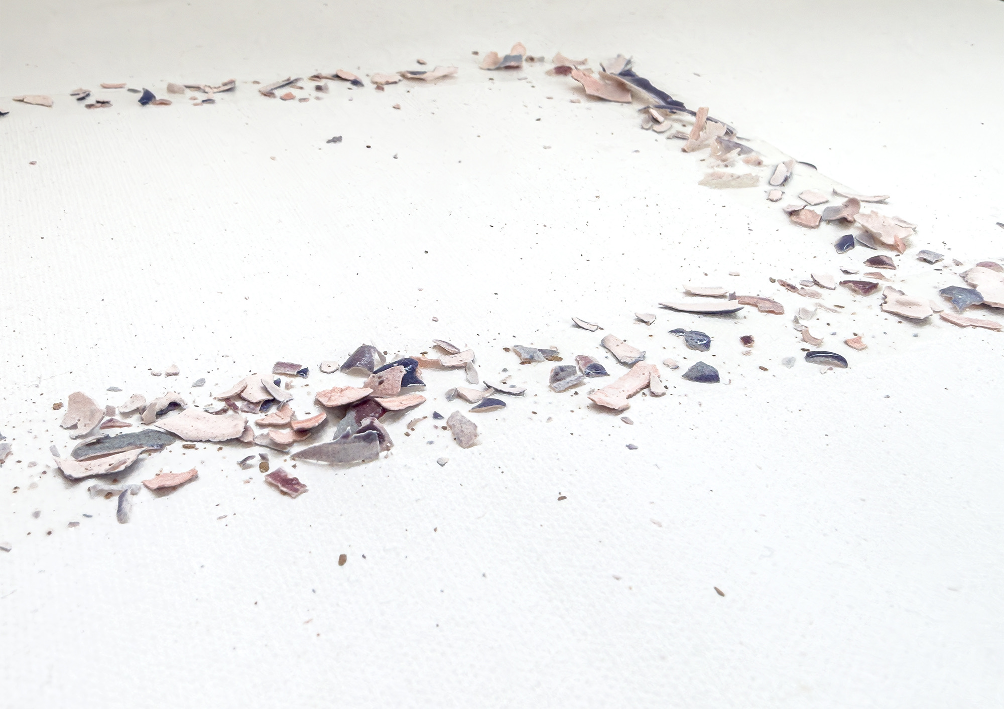 Detail: flakes of pink, grey and blue glaze lying along a line on the white surface