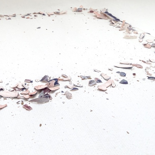 Detail: flakes of pink, grey and blue glaze lying along a line on the white surface